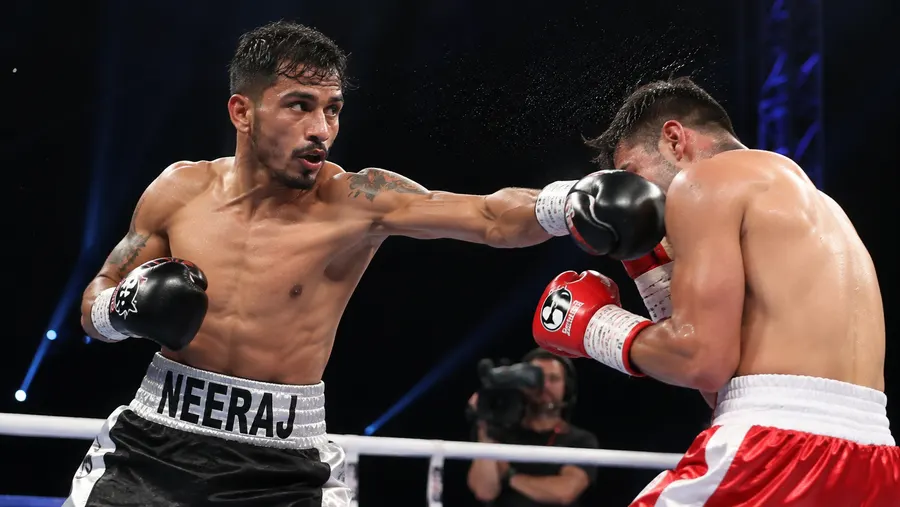 Neeraj Goyat throwing a punch during a bout, his name printed on his shorts