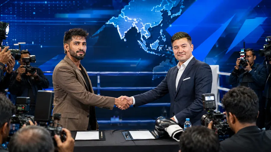 Neeraj Goyat shaking hands with a brand representative at a press event, photographers on both sides